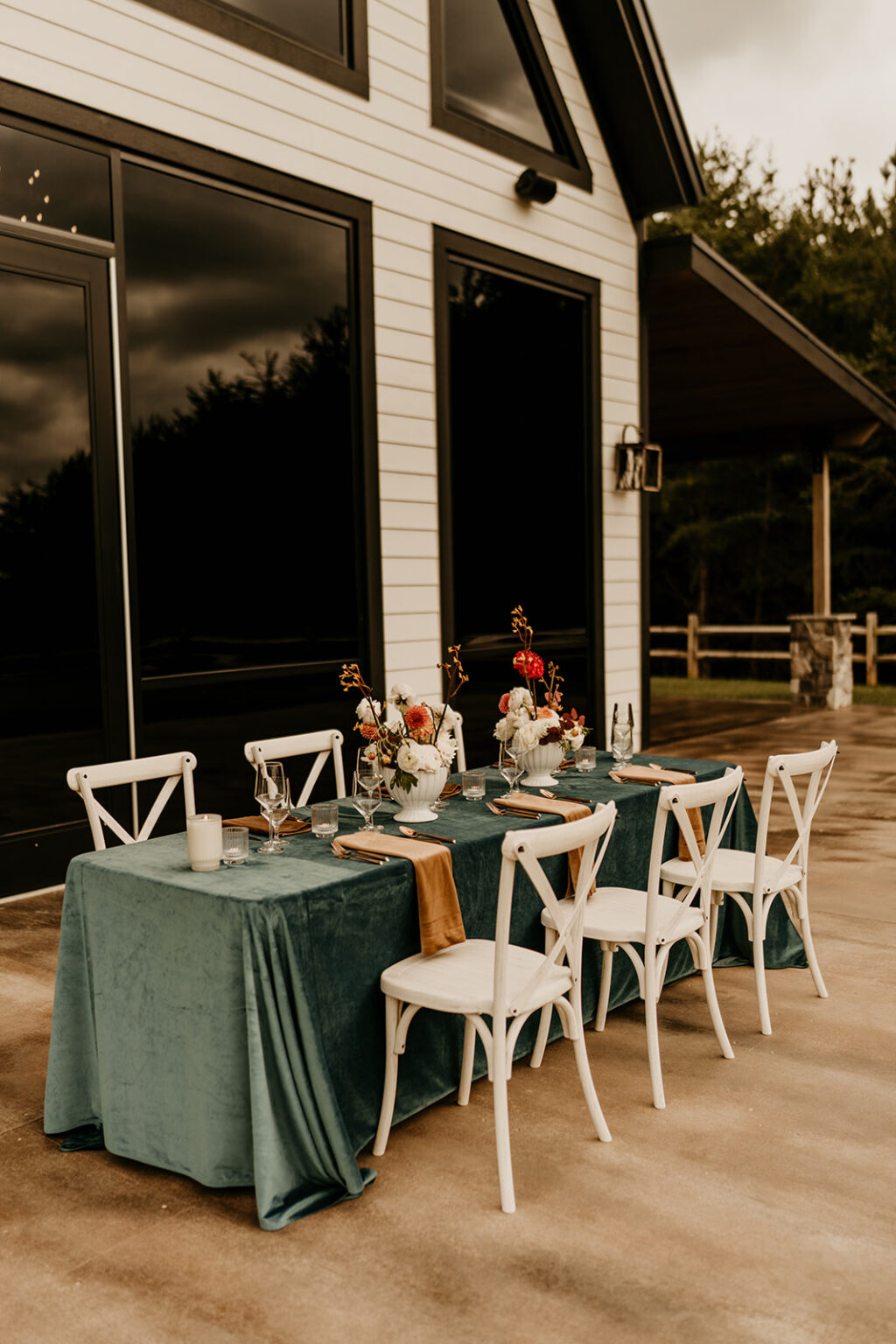 A table set up with white chairs and green tablecloth.