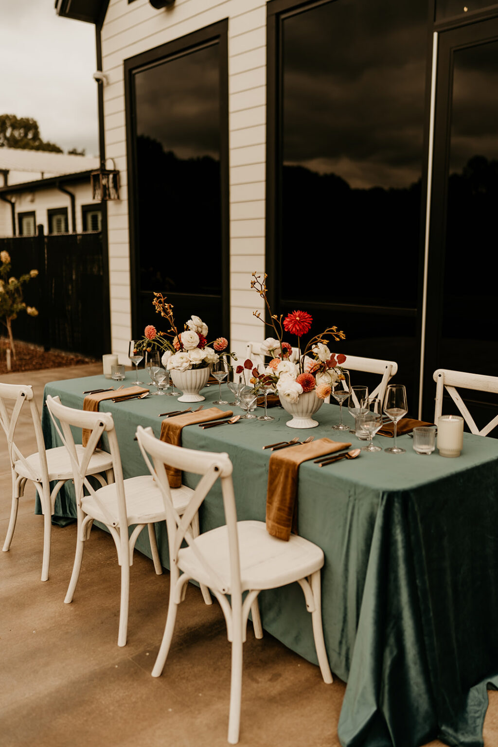 A table set with white chairs and green tablecloth.