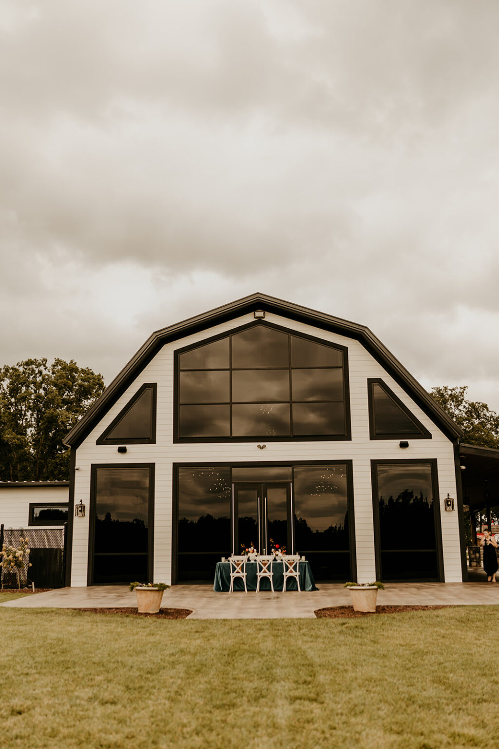 A large barn with tables and chairs outside of it.