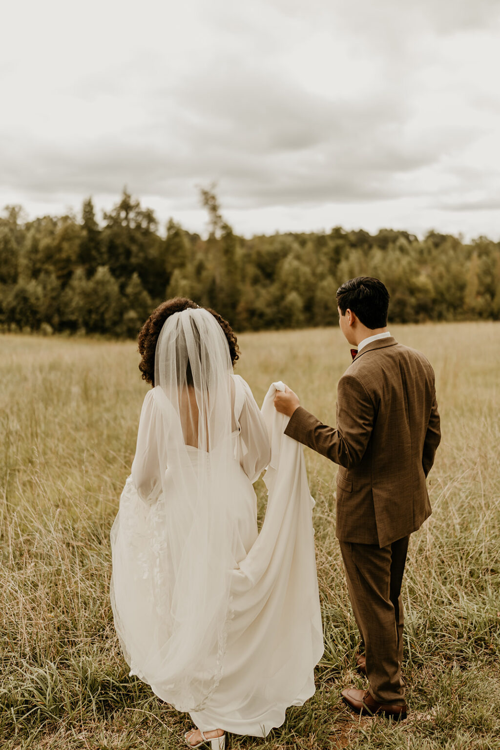 A man and woman walking through the grass.