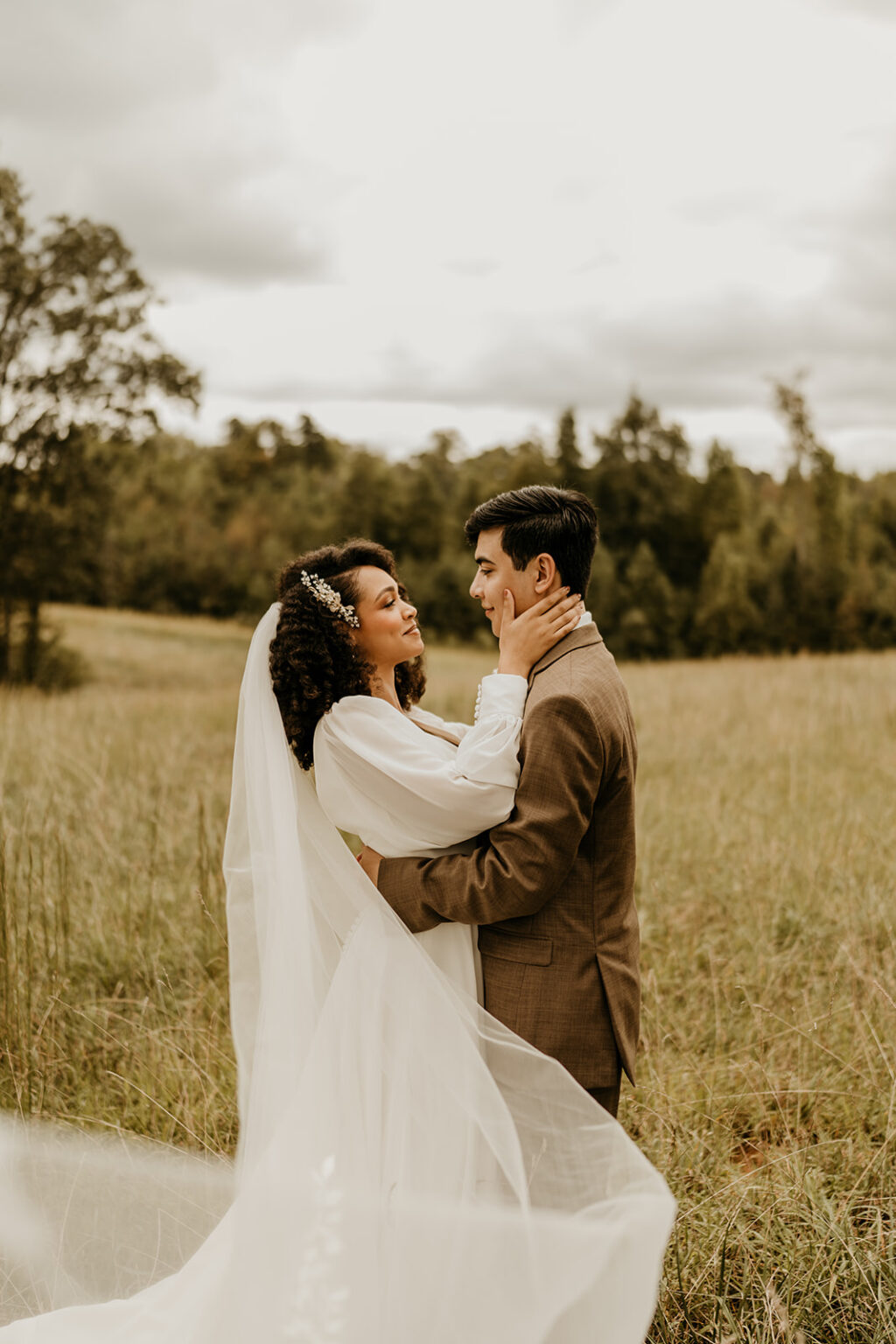 A bride and groom embracing in the middle of a field.