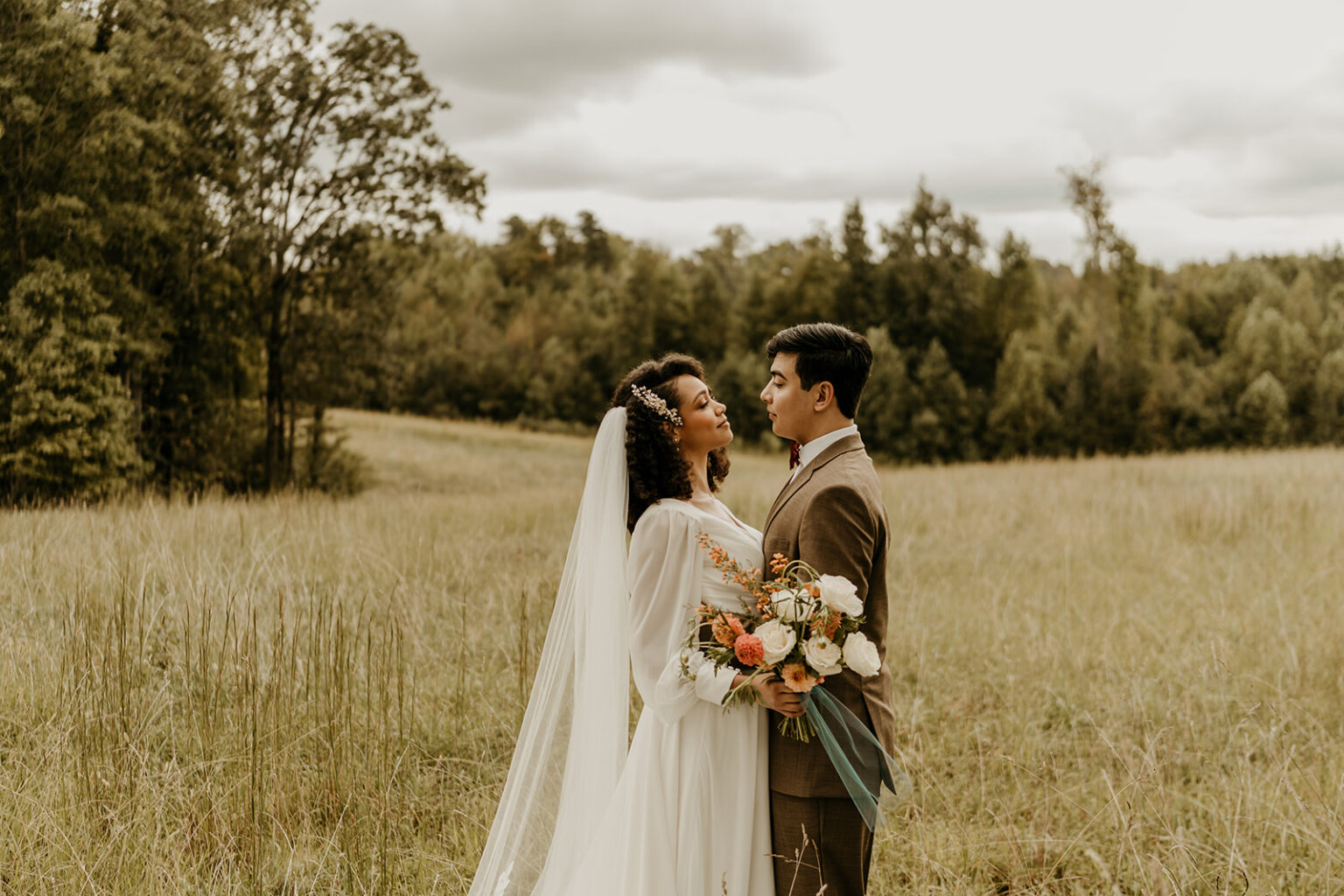 A bride and groom standing in the grass.