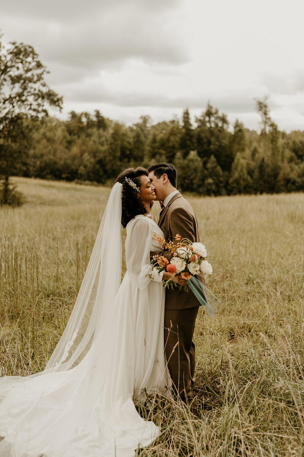 A bride and groom kissing in the middle of a field.