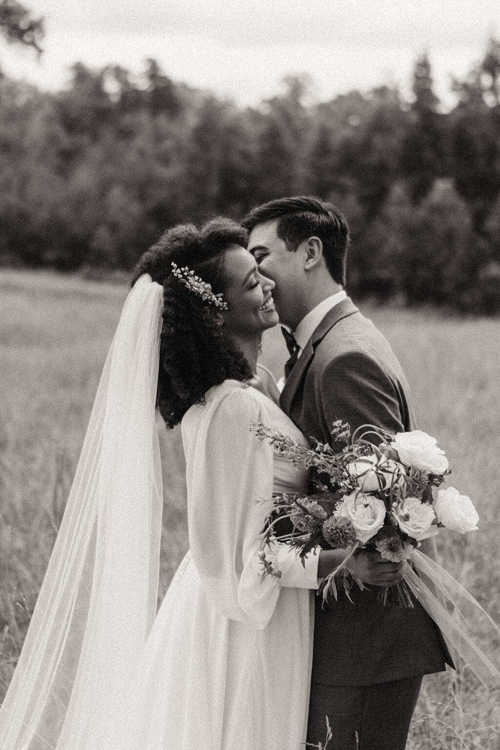 A man and woman kissing in the grass.