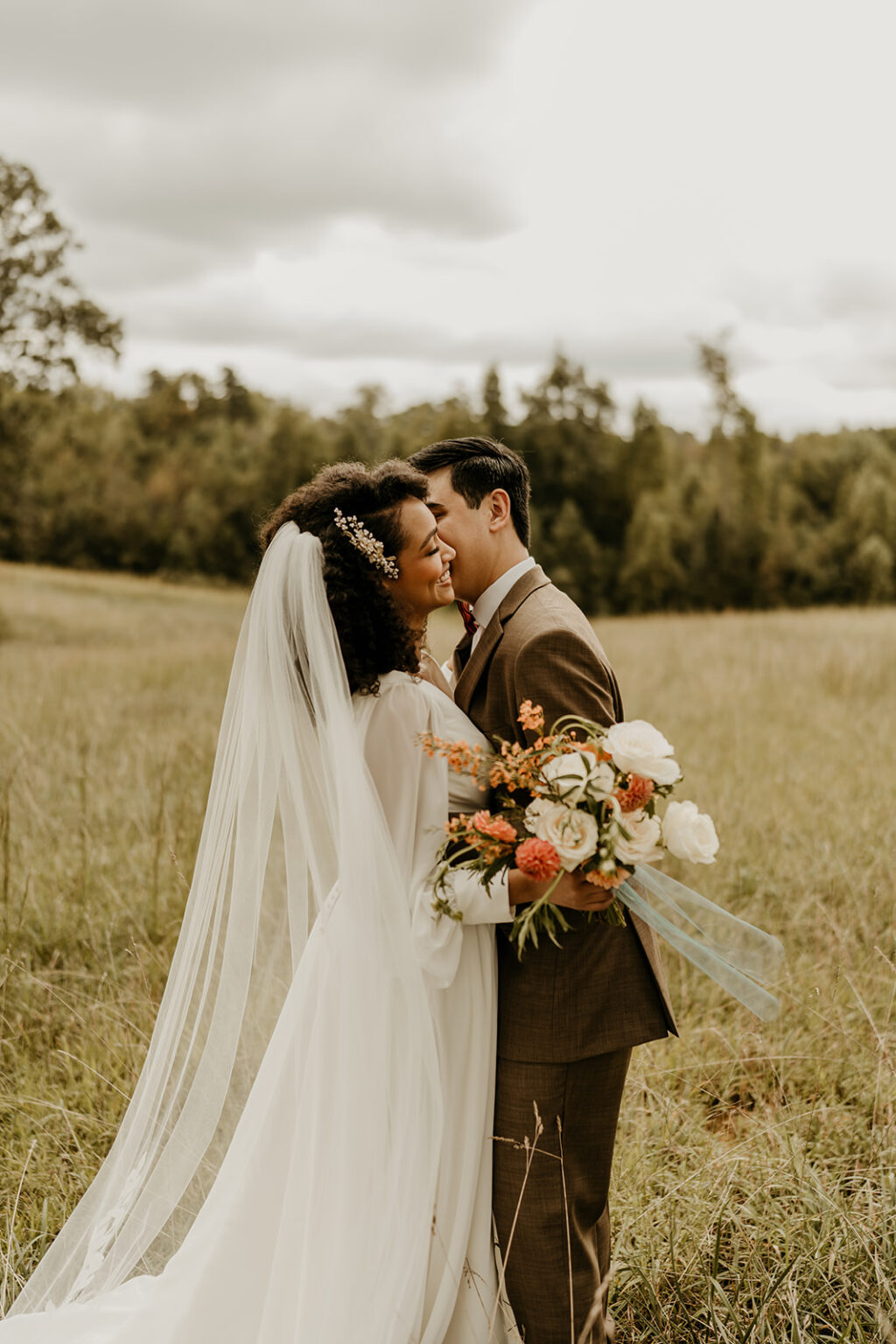 A bride and groom standing in the middle of a field.