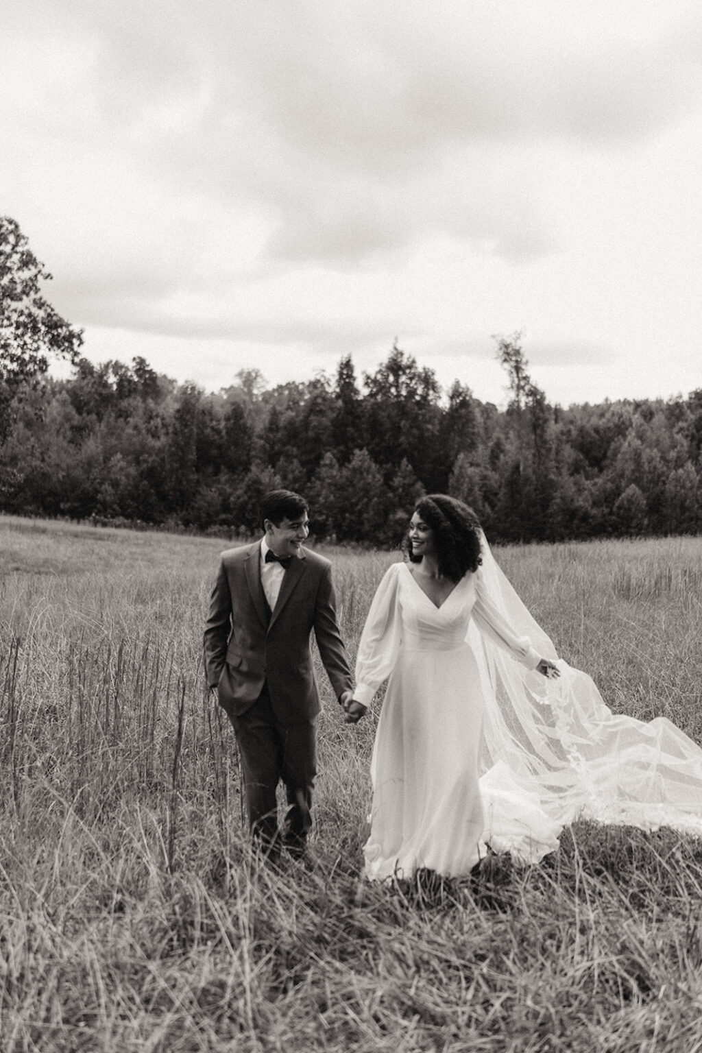 A man and woman holding hands in the middle of a field.