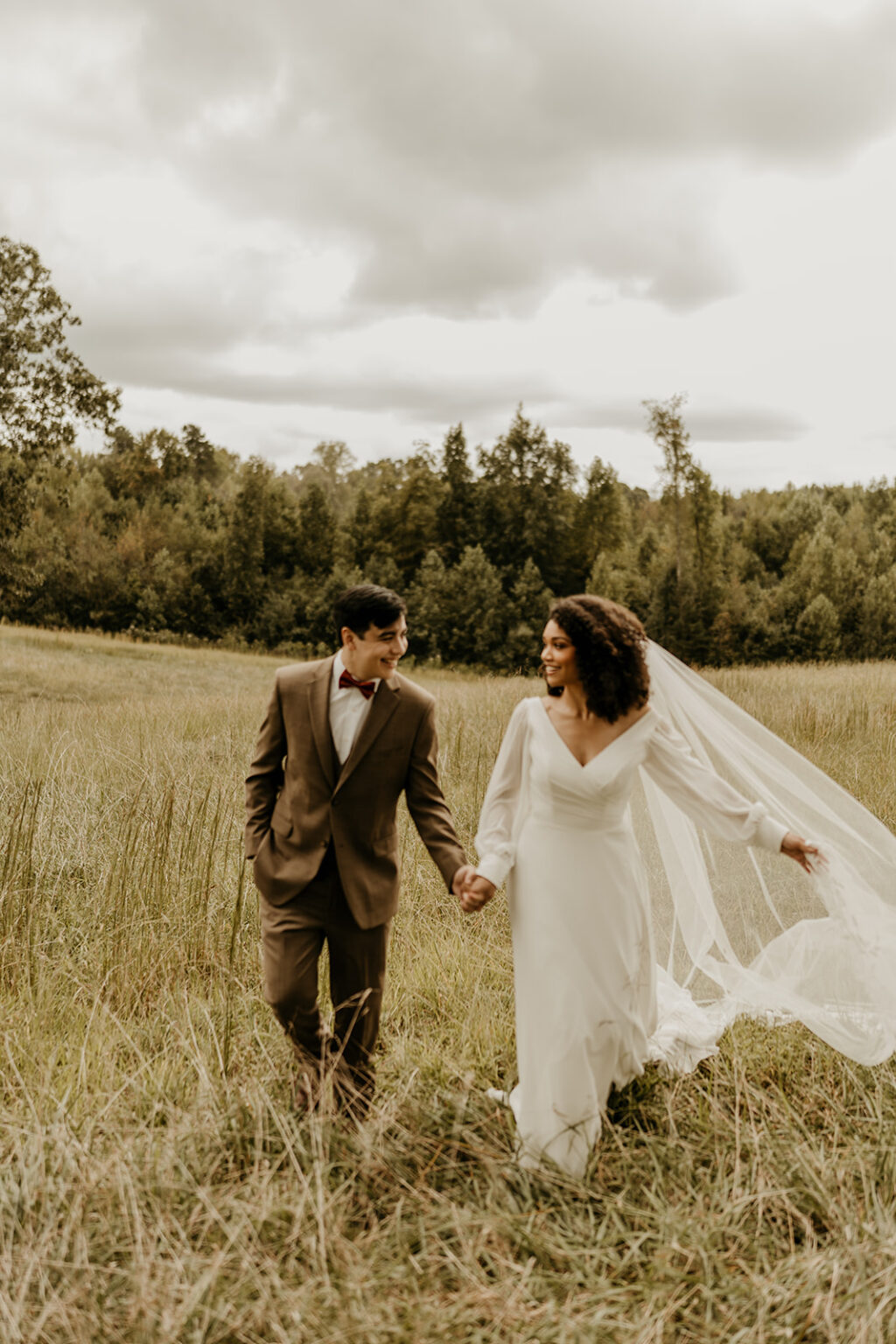 A man and woman holding hands in the middle of a field.