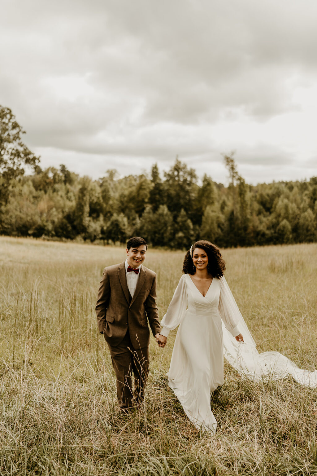 A man and woman holding hands in the middle of a field.