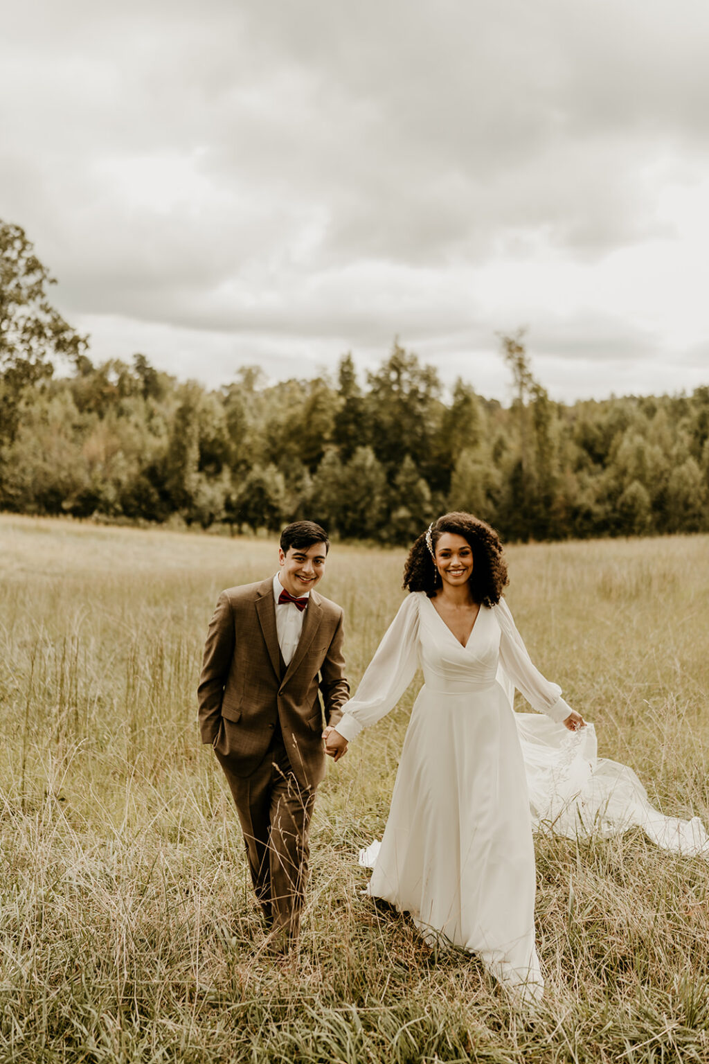 A man and woman holding hands in the middle of a field.