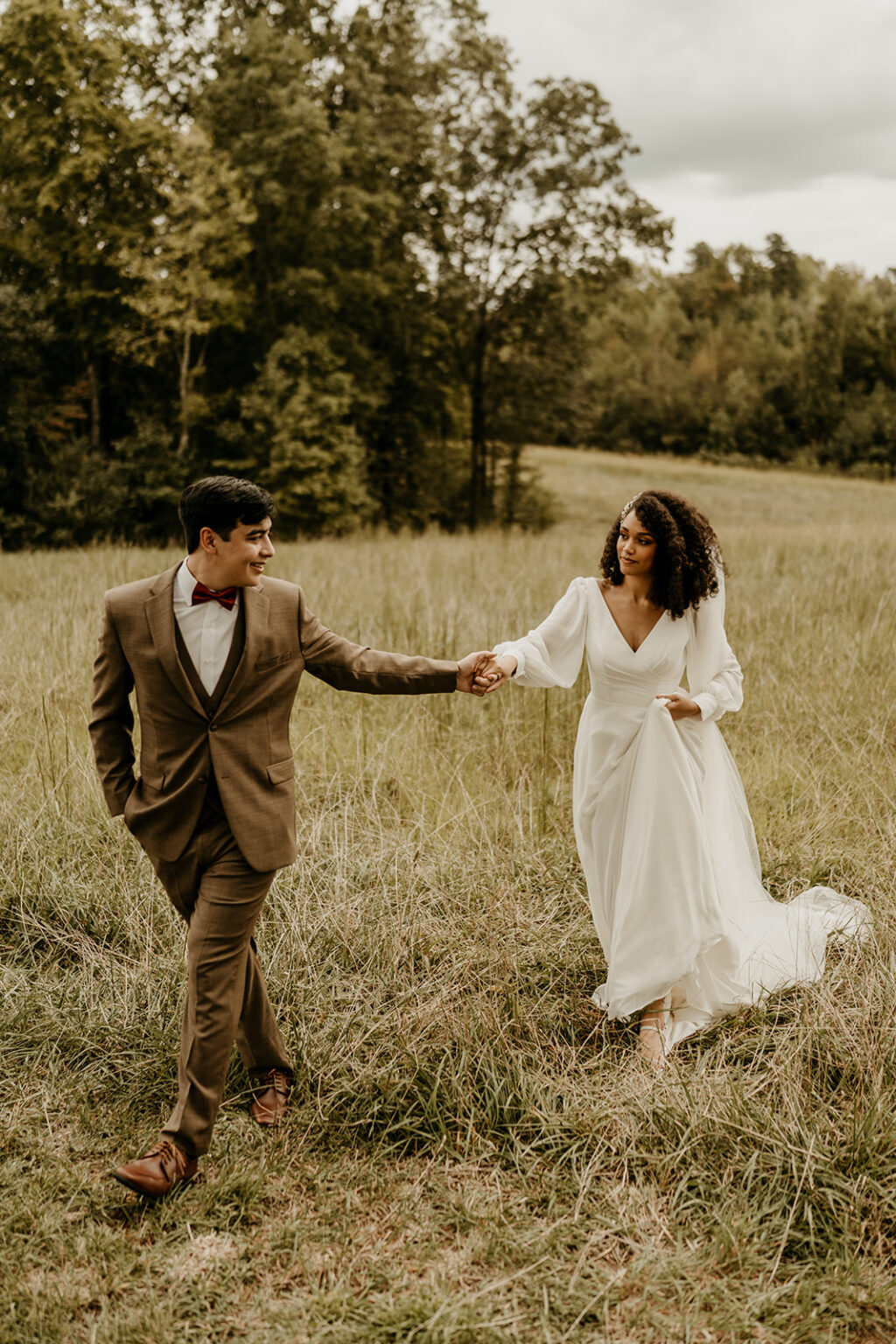 A man and woman holding hands in the middle of a field.