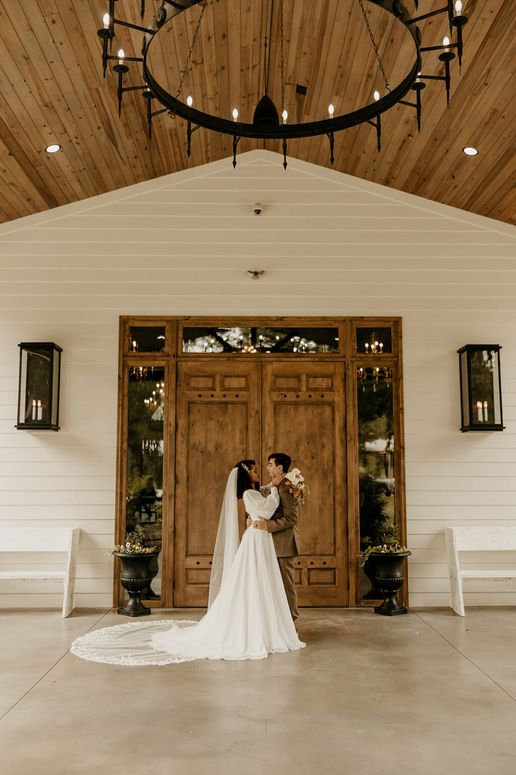 A bride and groom kissing in front of the door.