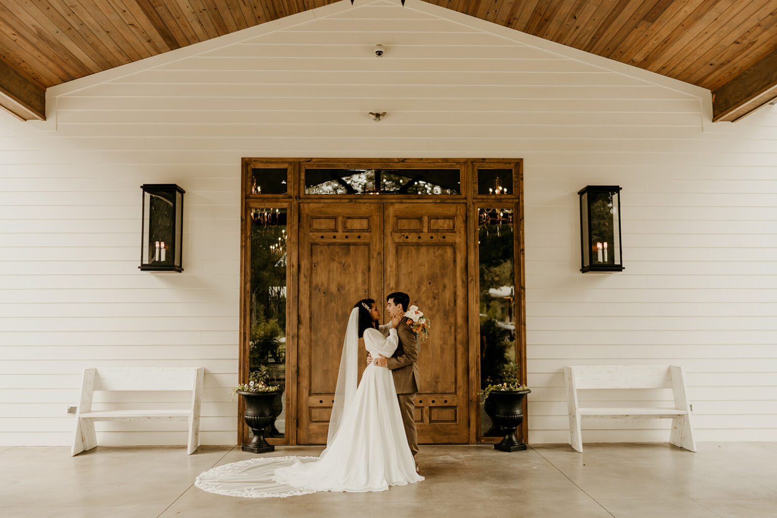 A bride and groom pose for a picture in front of the door.