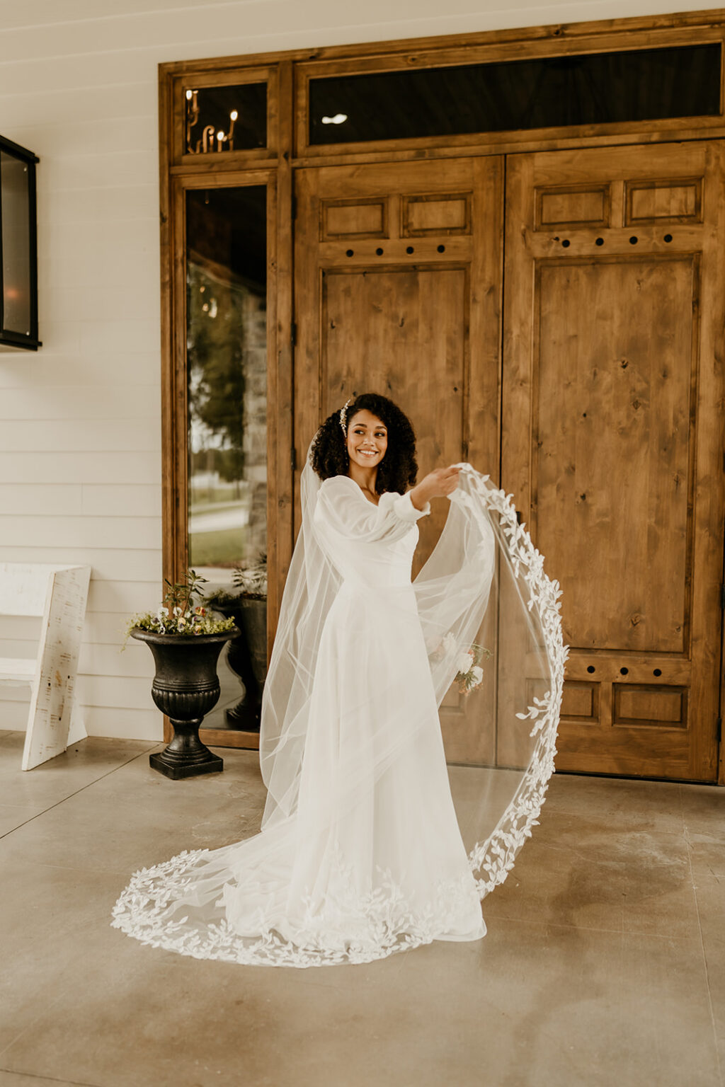 A woman in a white dress holding onto a veil