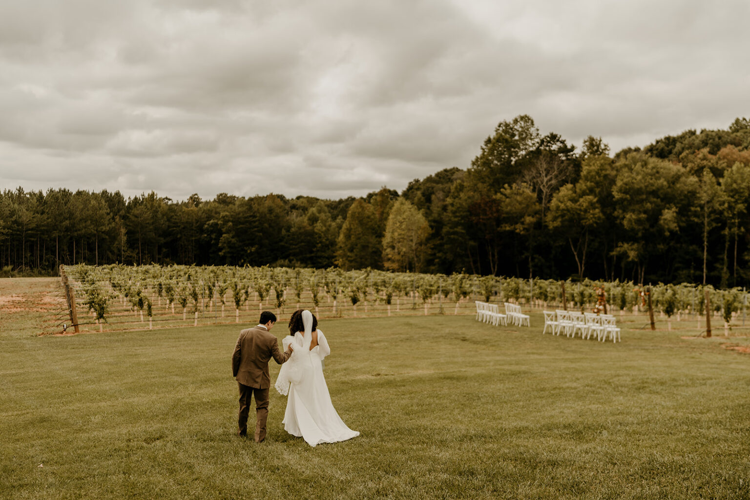 A couple walking in the grass near some trees