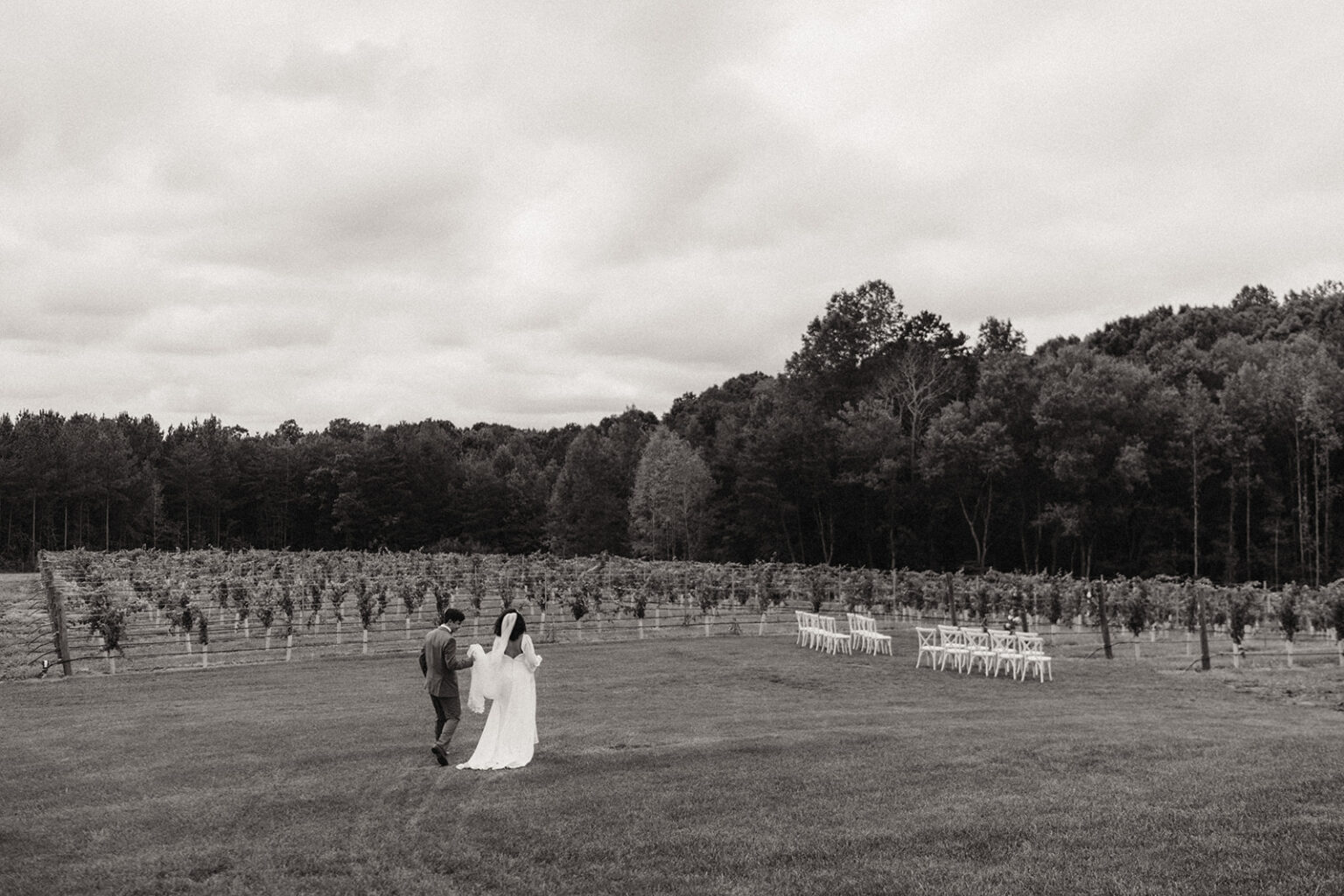 A couple walking in the grass near some trees