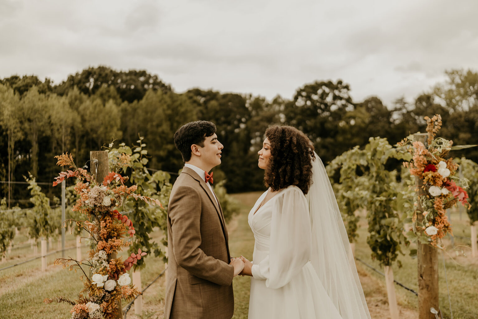 A man and woman holding hands in front of some trees