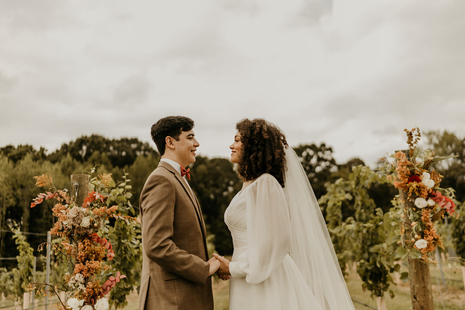 A man and woman holding hands in front of trees.