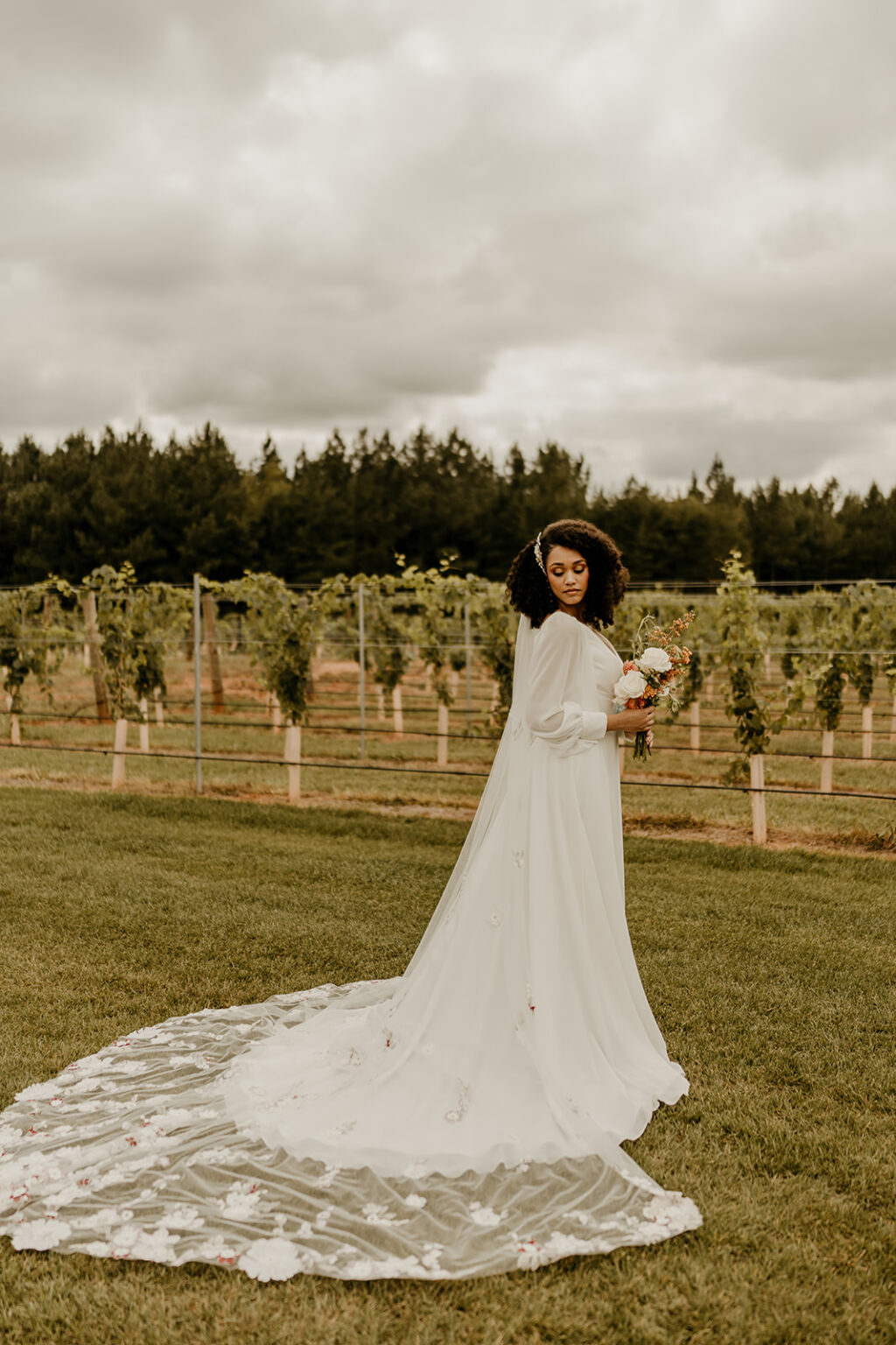 A woman in a white dress standing on top of a grass covered field.