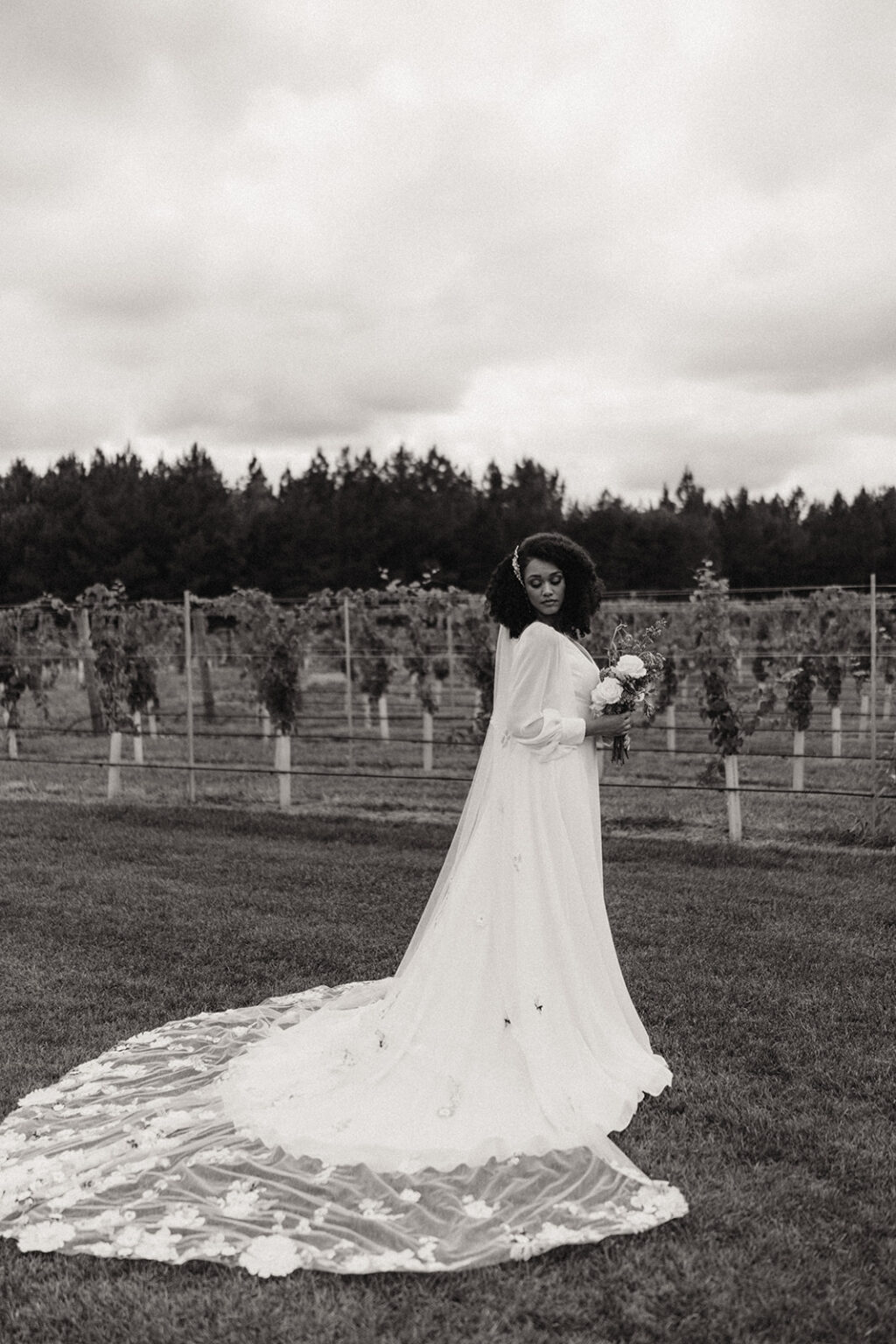 A woman in a long white dress standing on top of grass.