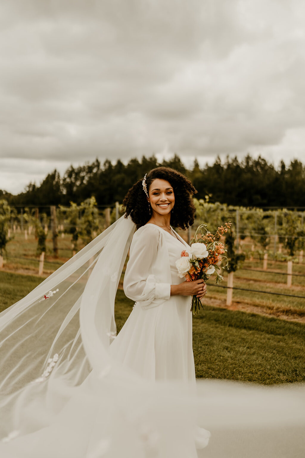 A woman in white dress standing next to a field.