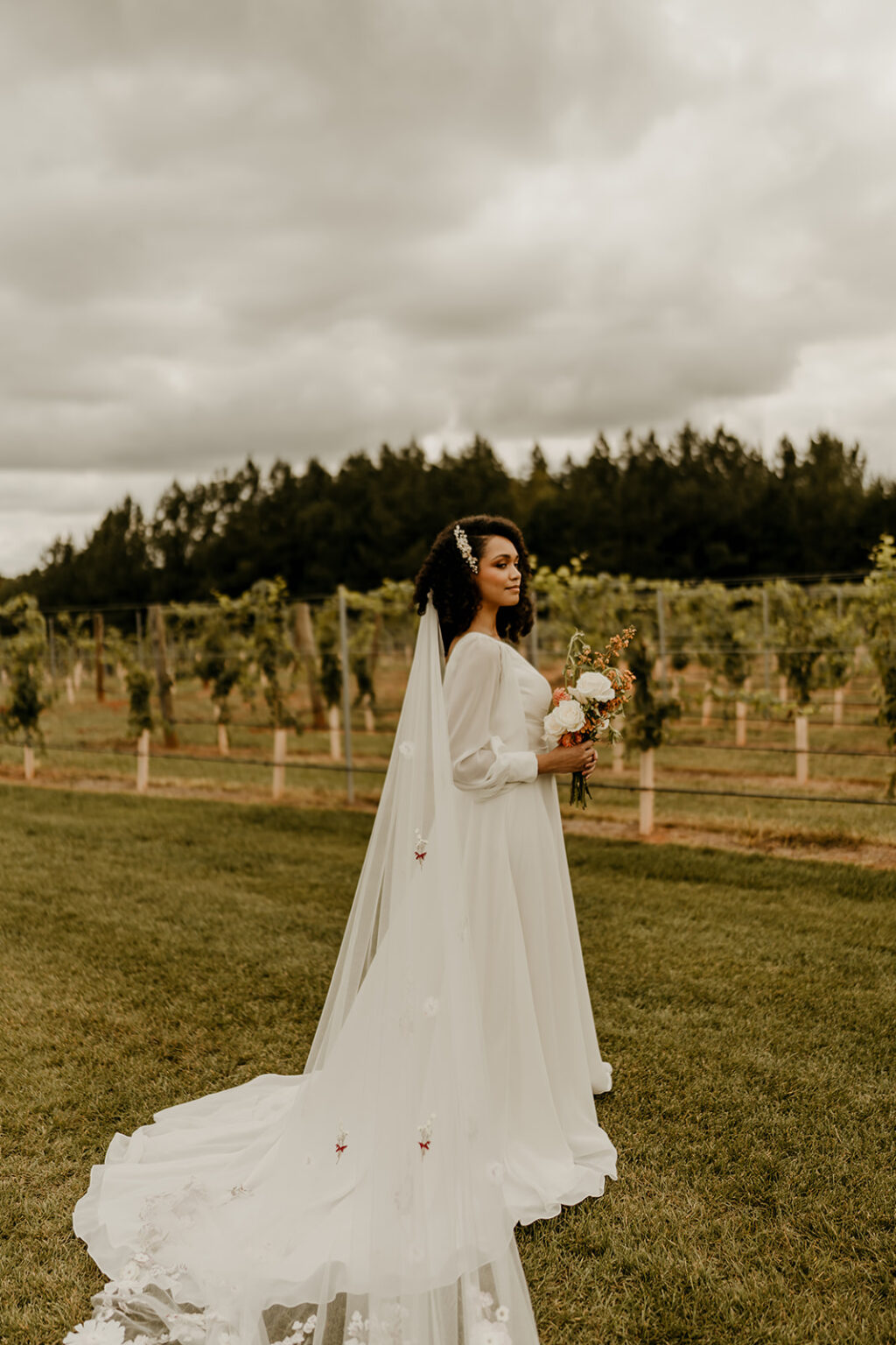 A bride in her wedding dress standing on the grass.