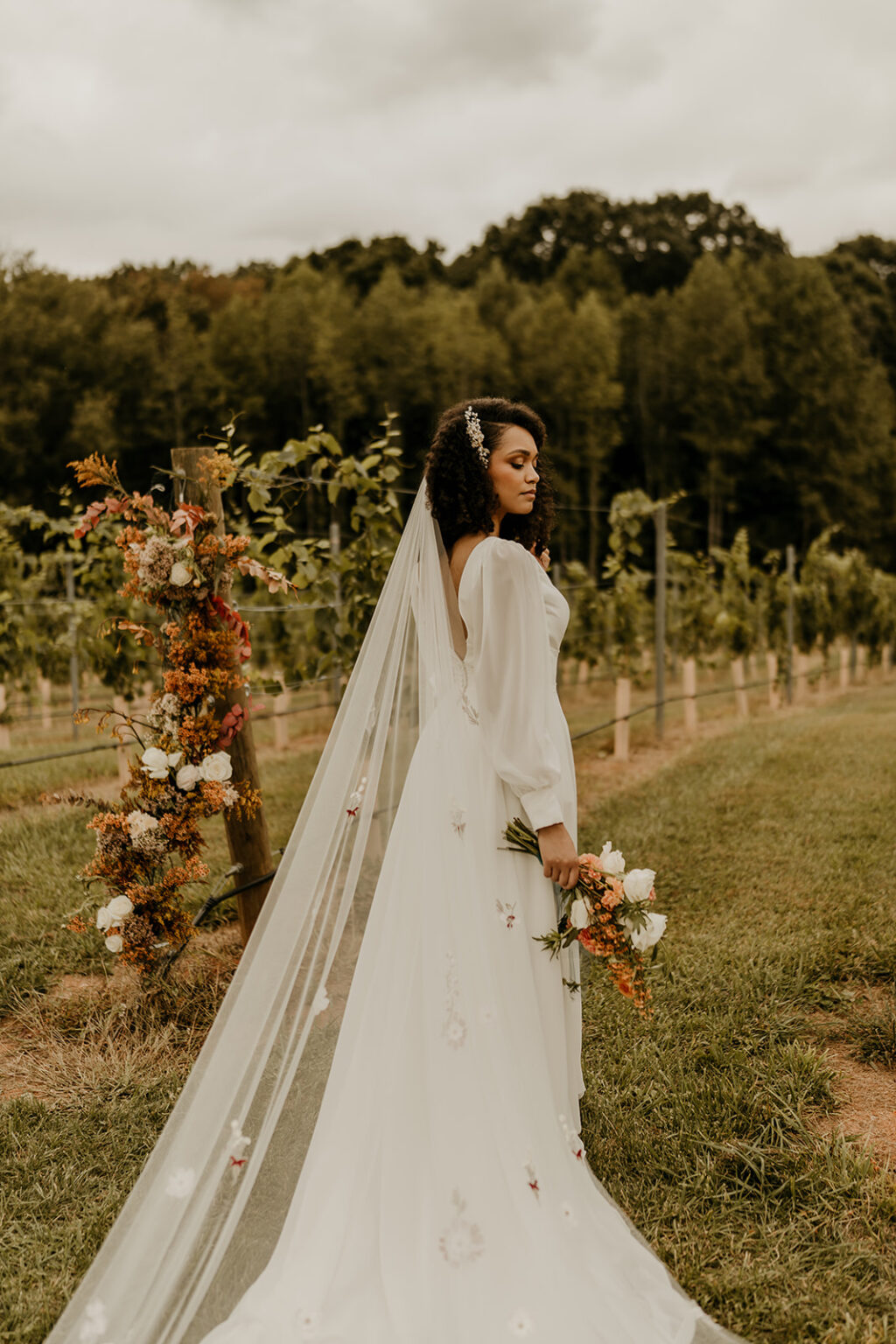 A bride in a white dress and veil standing outside