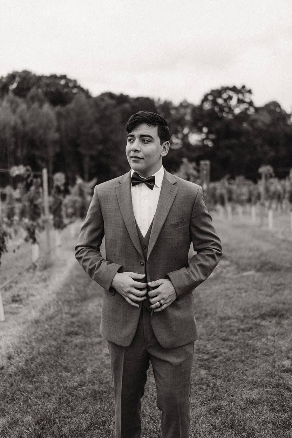 A man in a suit and bow tie standing outside.