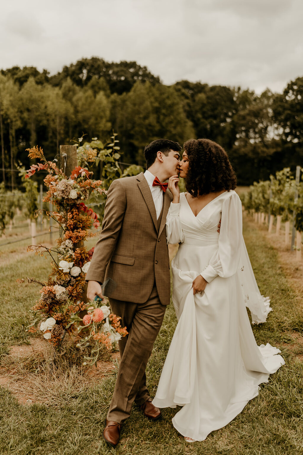 A man and woman kissing in front of a tree.