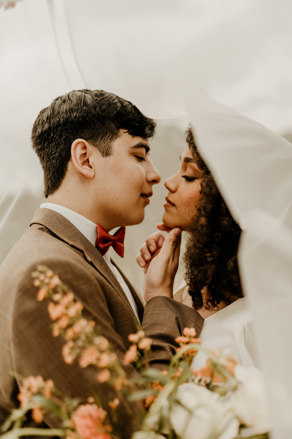 A man and woman kissing under an umbrella.