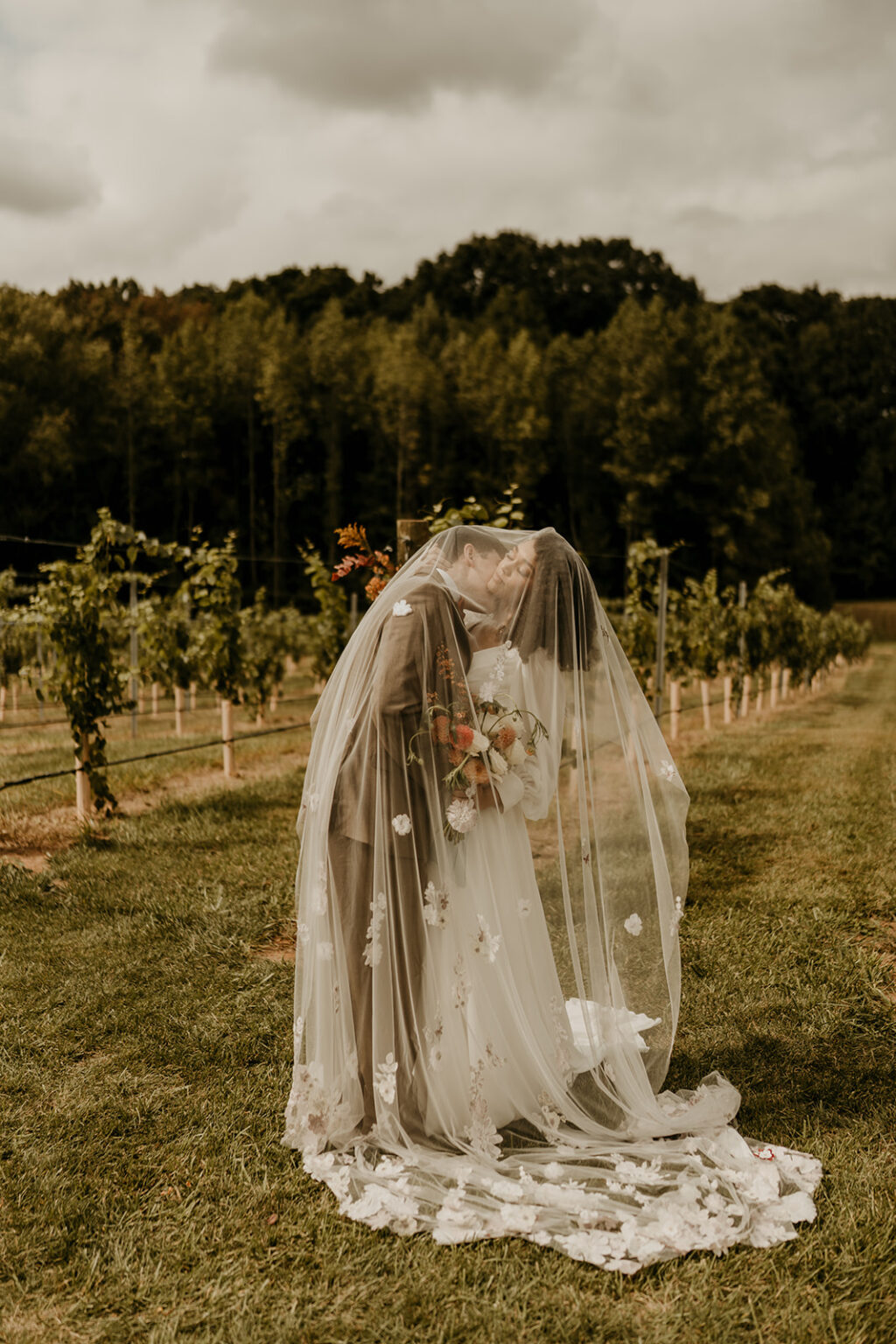 A bride in a white dress and veil kissing her groom.