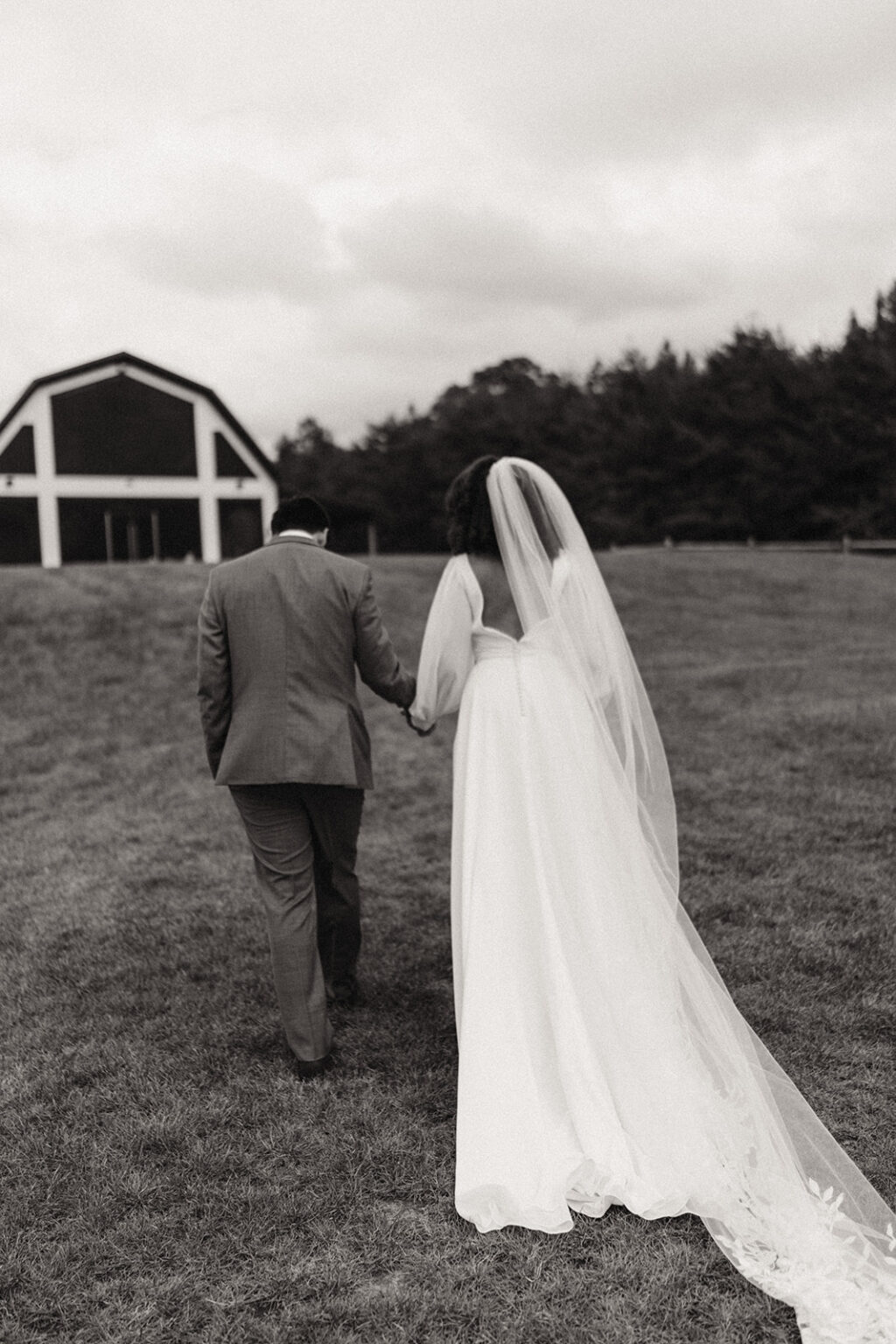 A man and woman walking in front of a barn.