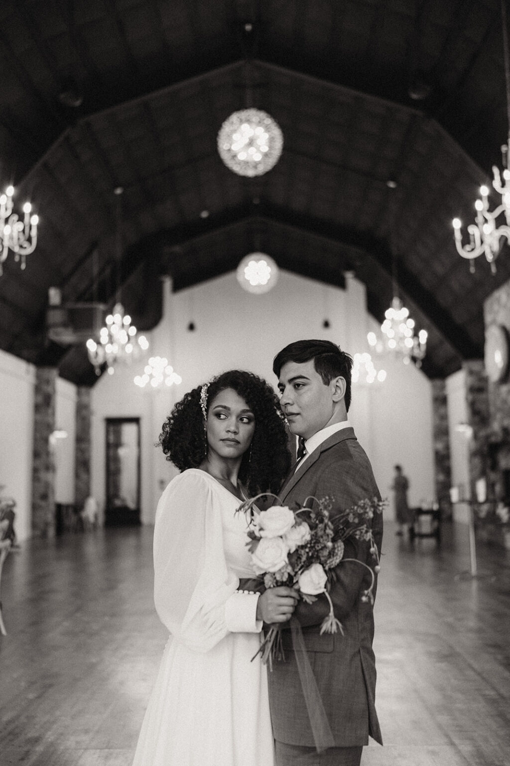 A man and woman standing in front of chandeliers.