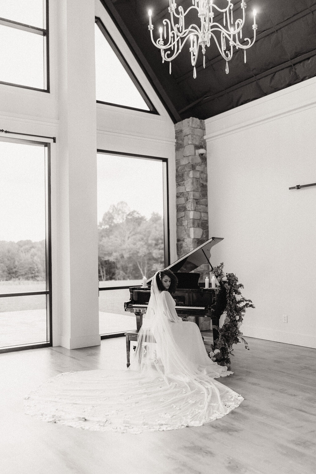 A bride and groom sitting at the piano in front of windows.