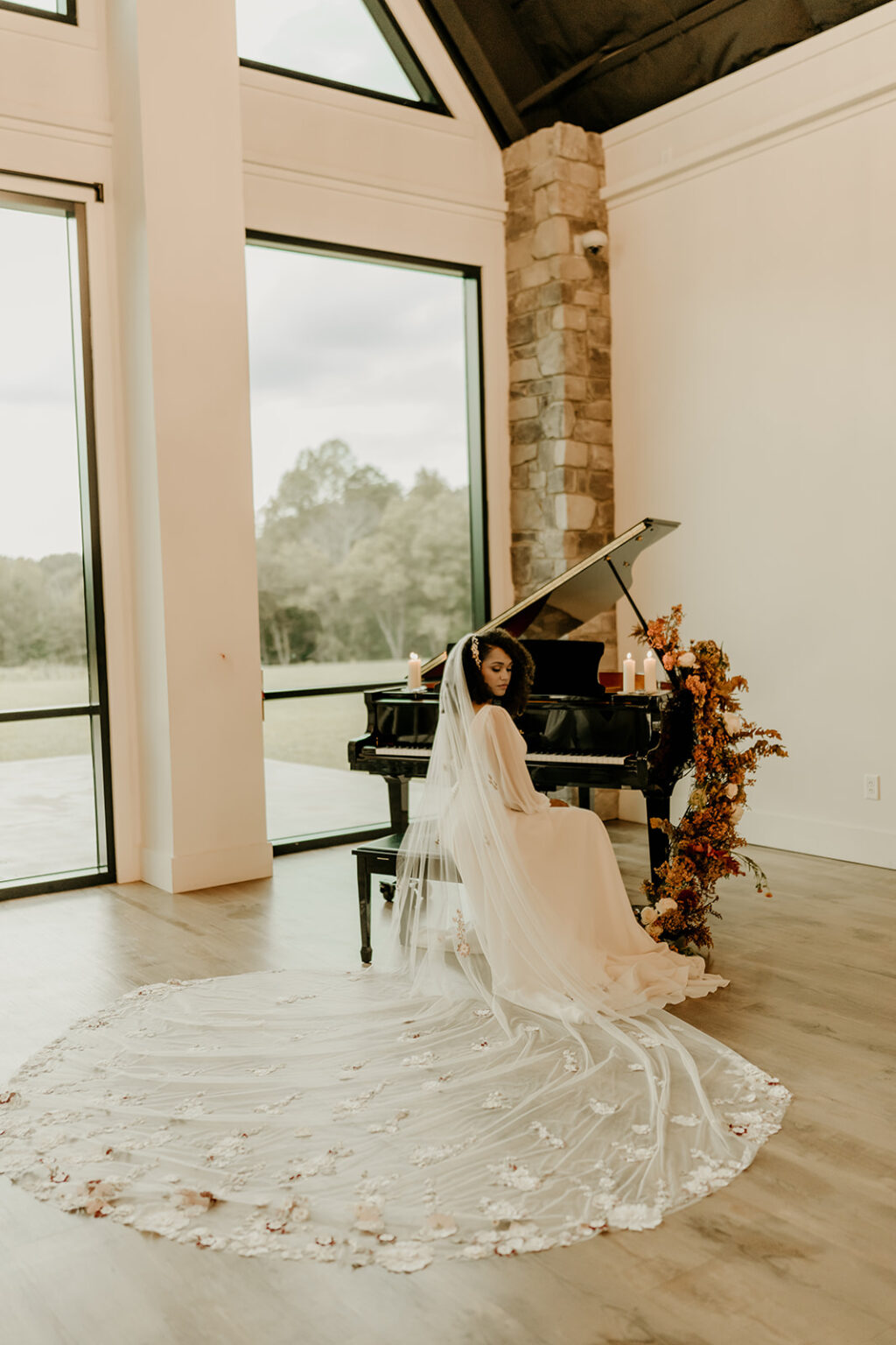 A bride in a white dress is sitting by the piano