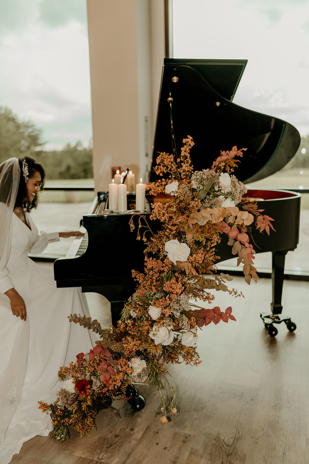 A woman in white dress standing next to a piano.