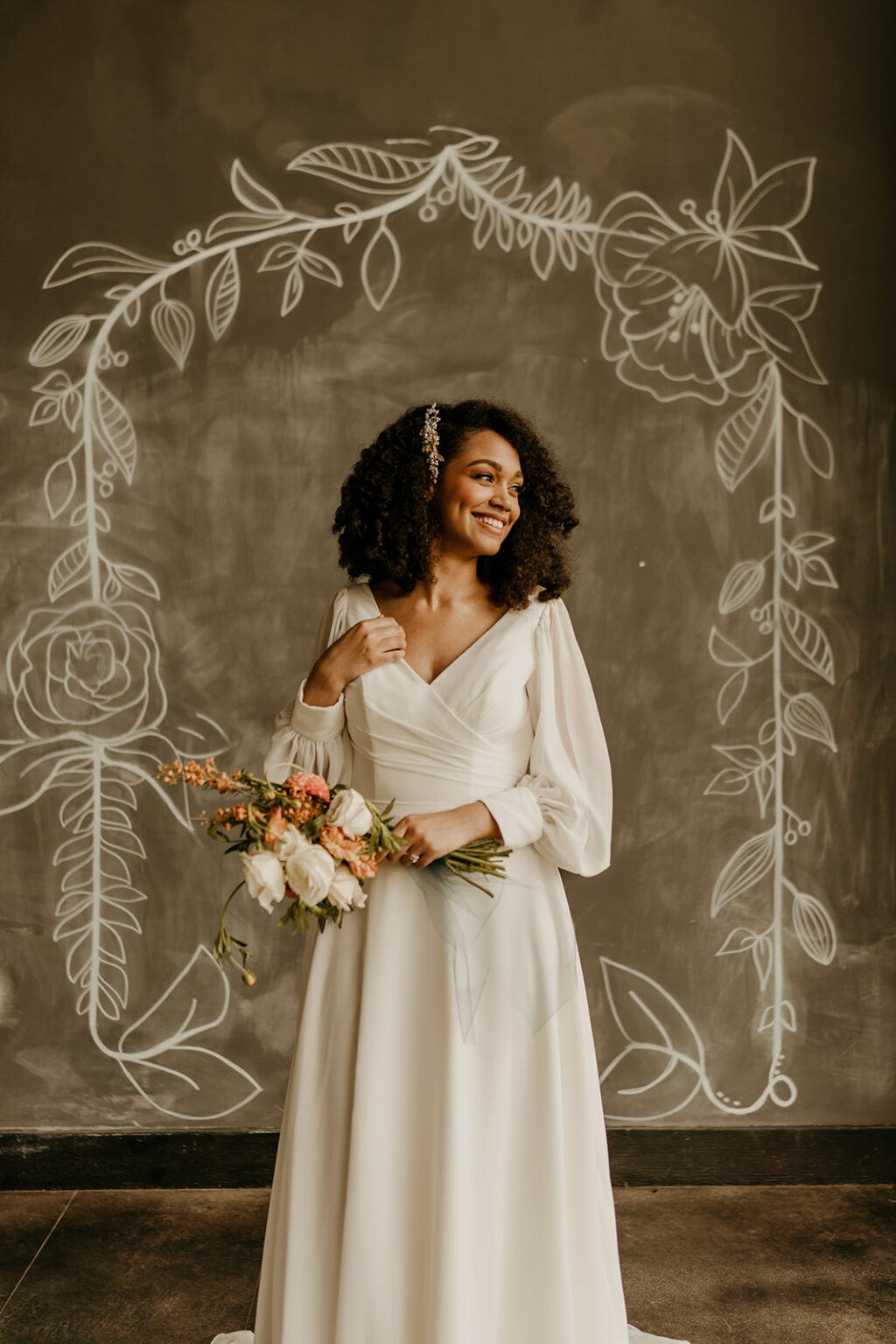 A woman holding flowers in her hand and wearing a white dress.