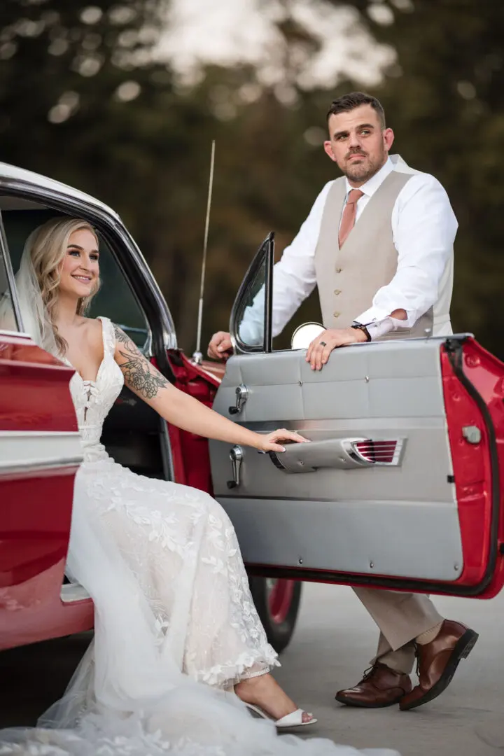 A man and woman in wedding dress getting into a car.