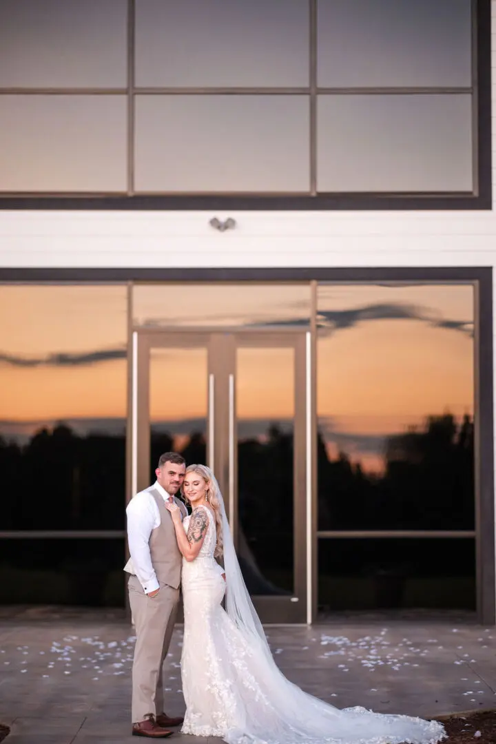 A couple posing for a picture in front of an entrance.