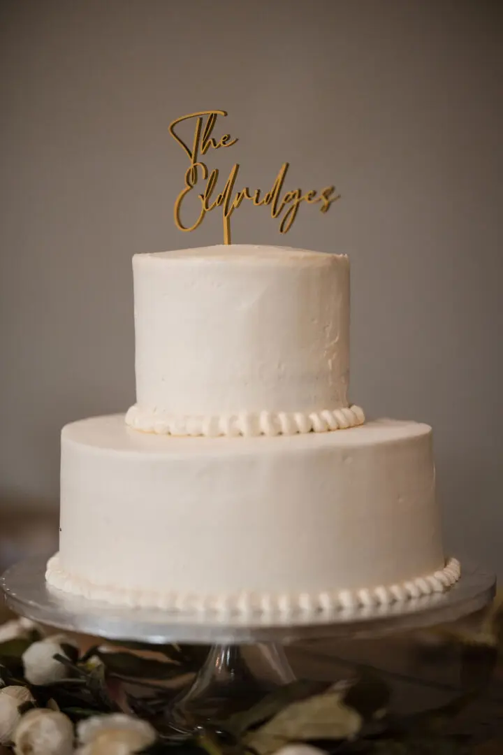 A white two tiered cake with the name " she."