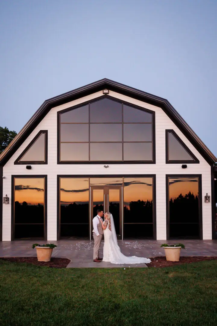 A bride and groom pose for the camera outside of their wedding venue.