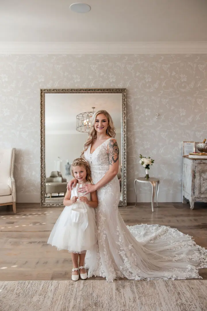 A woman and girl in wedding dress posing for the camera.