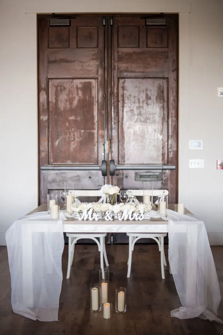 A couple of tables with two chairs and candles on top.