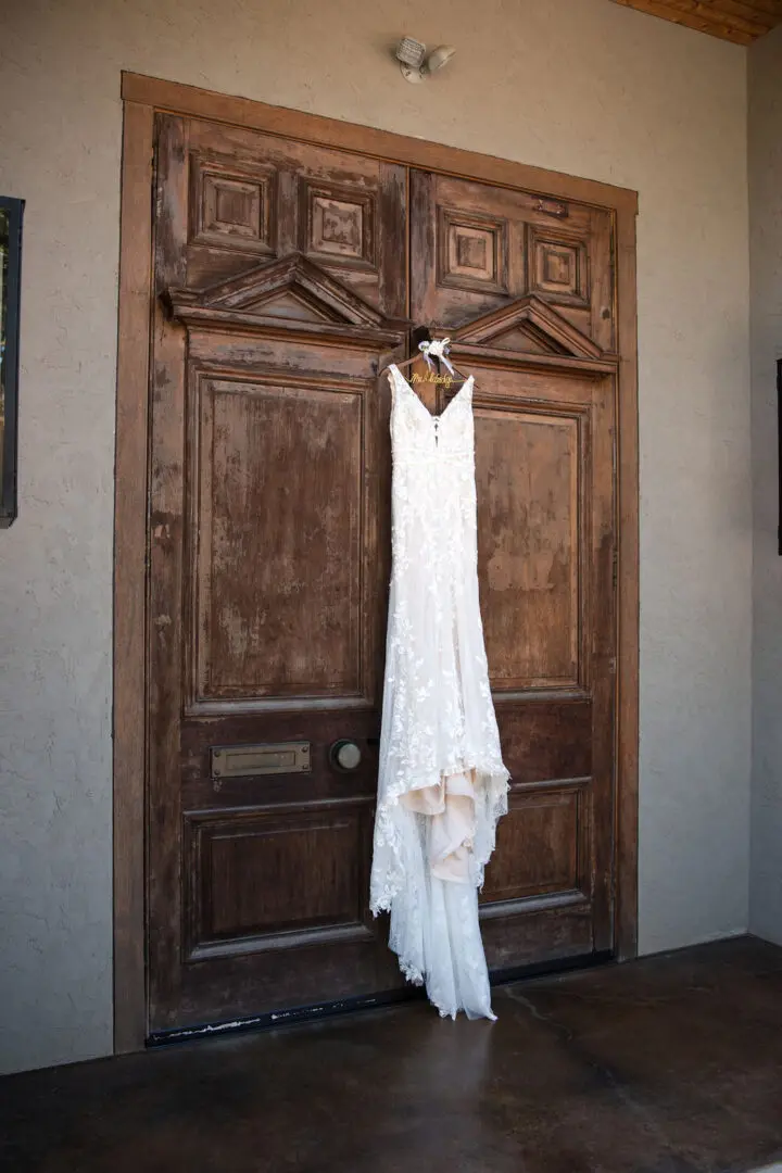 A wedding dress hanging on the door of a building.