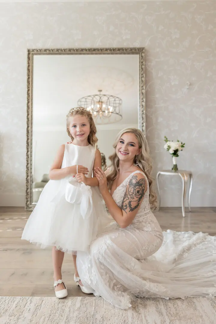 A woman and girl in wedding dress posing for the camera.