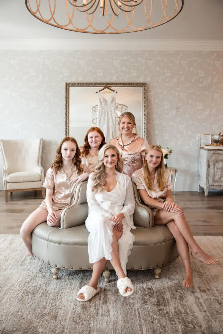 A group of women sitting on top of a round couch.