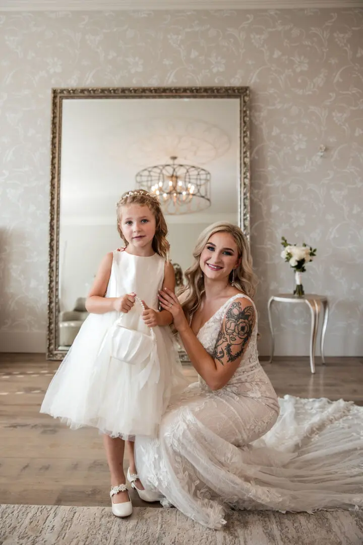 A woman and girl in white dresses posing for the camera.