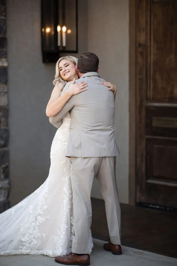 A man and woman hugging each other in front of a door.