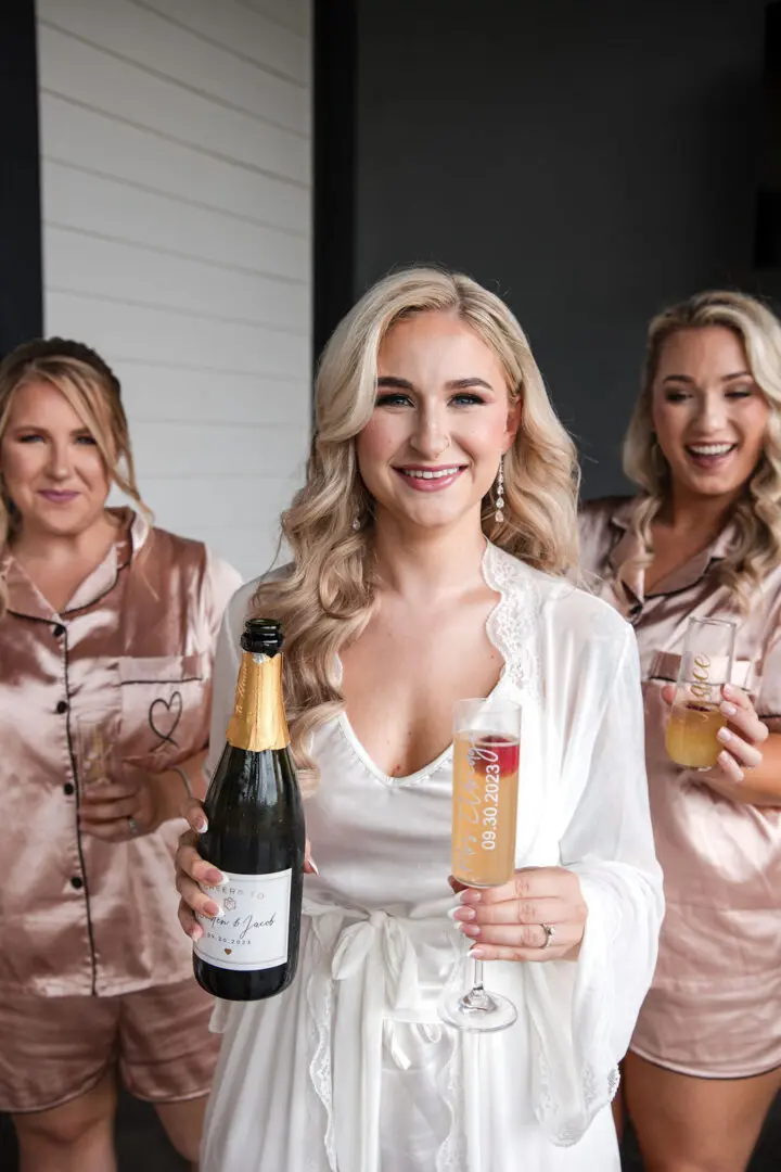 A woman holding a bottle of champagne next to two other women.