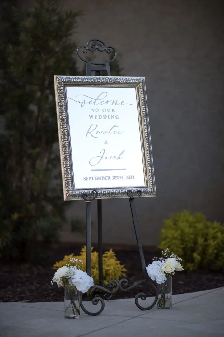 A sign that is on the ground with flowers.