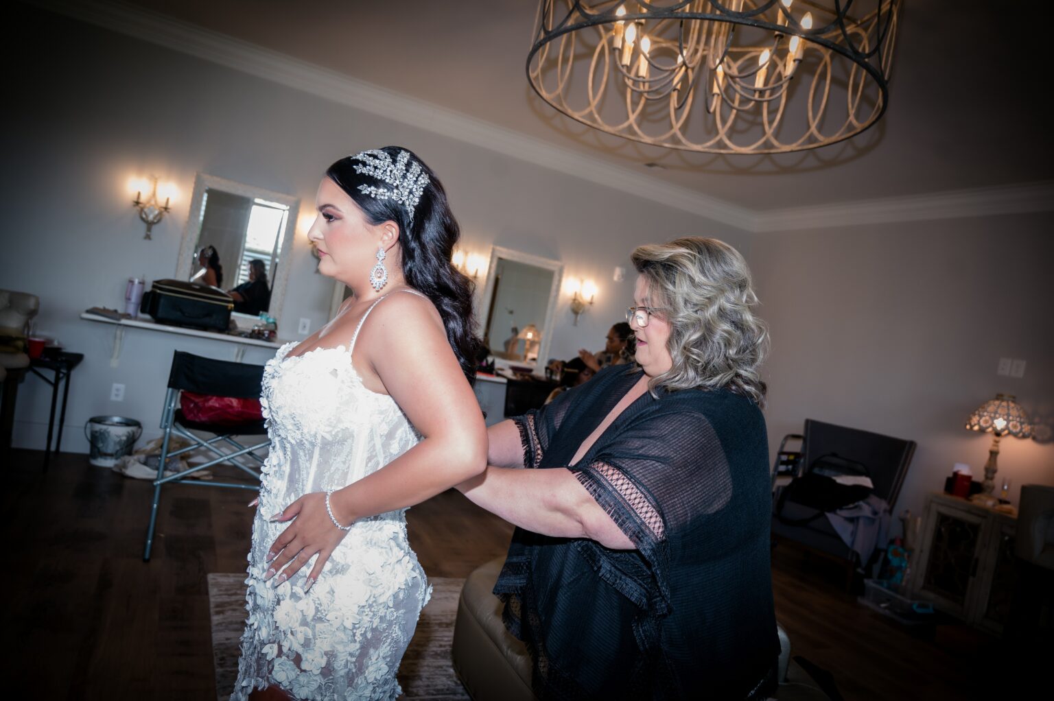 A woman helping another woman put on her dress.